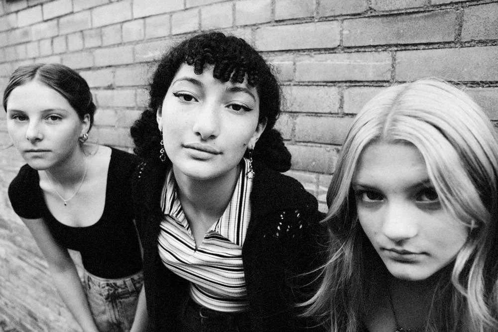 Clara, Violet and Lola against a brick wall